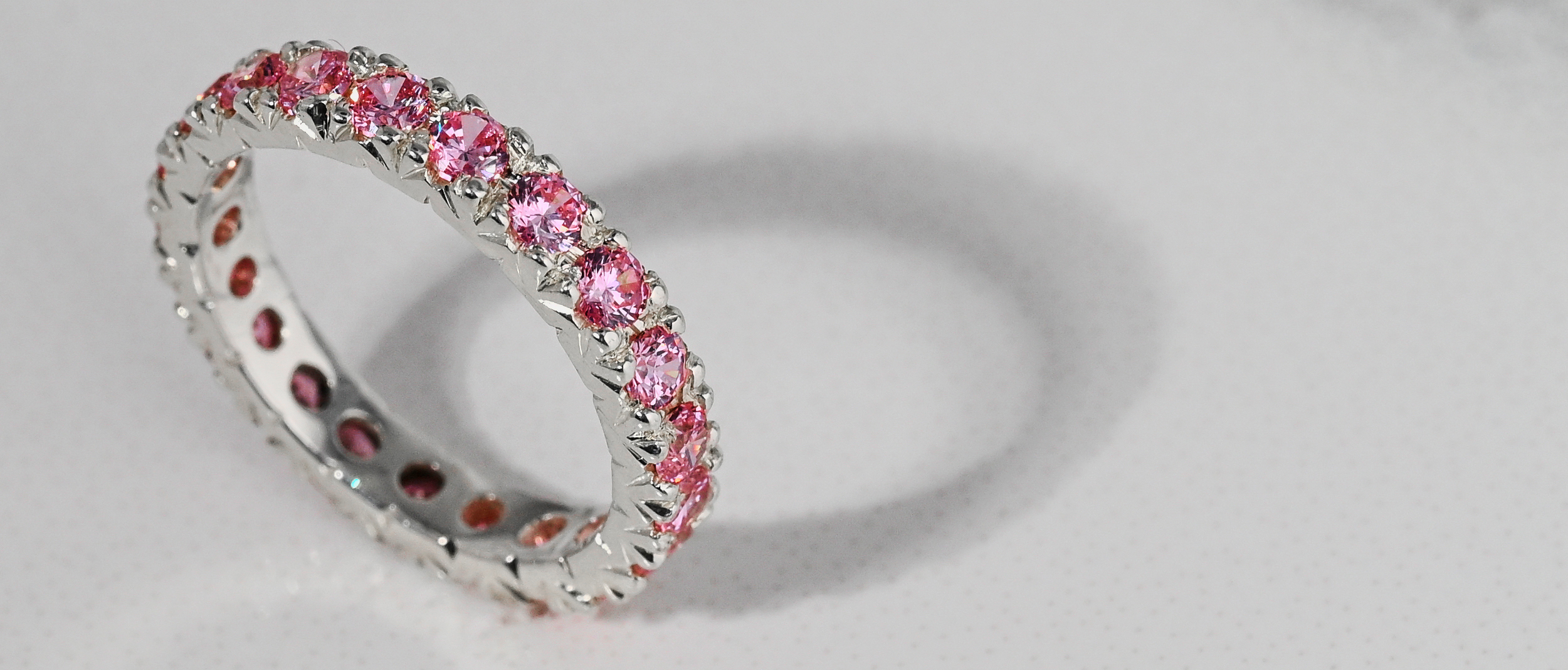 Sterling silver, fishtail cut eternity ring with pink sapphire gemstones 