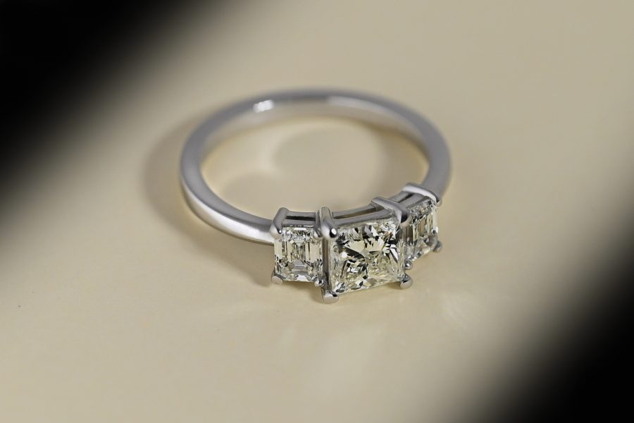 Three stone, princess cut diamond & platinum engagement ring showing shank and stone setting